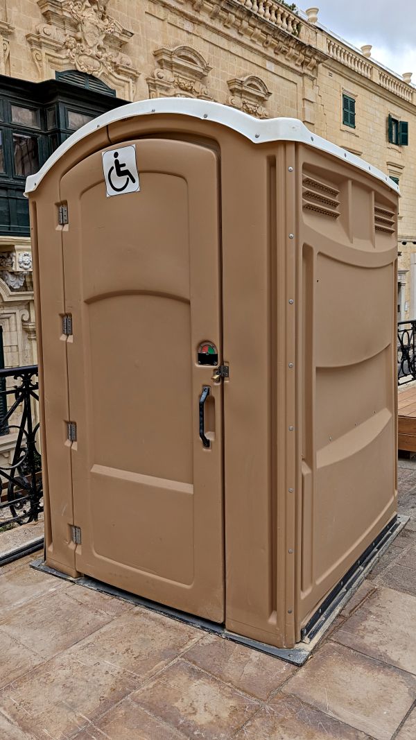 Construction site porta potty placed beside site fencing in Central Texas